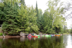 Kayaks on a lake near forested shoreline